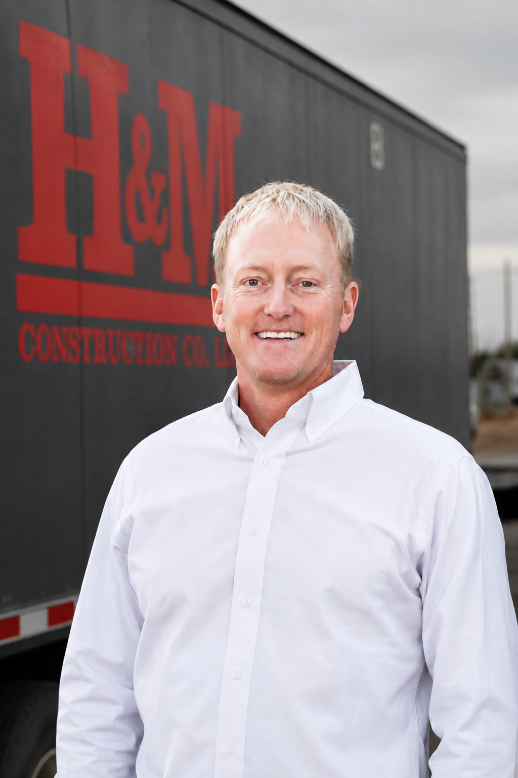 Thomas Ruffin, project manager at H&M Construction, standing in front of an H&M equipment trailer
