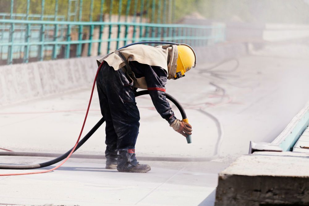 Crew member applying industrial coating with a spray hose