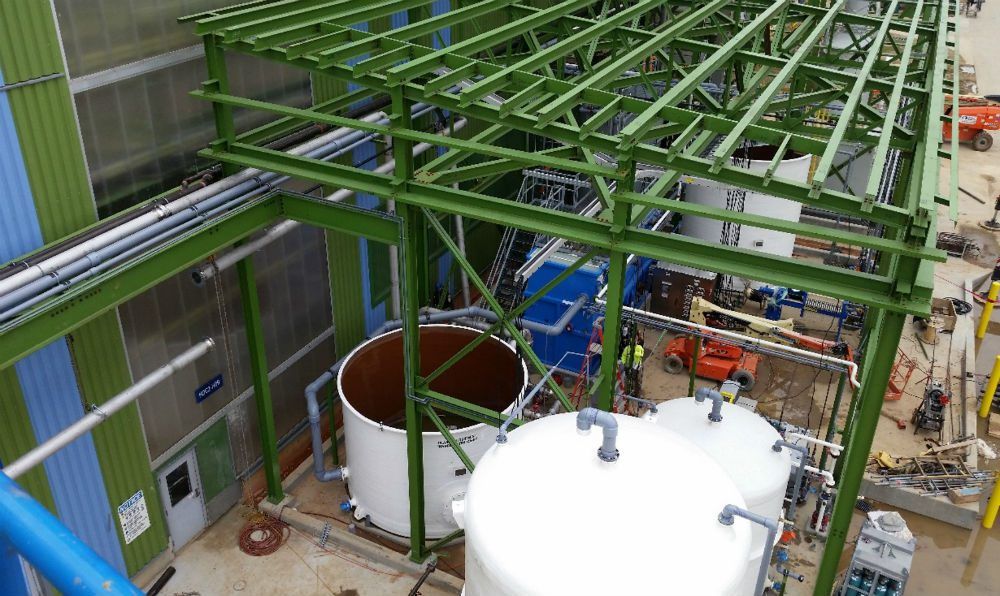 Large white process tank under an open roof at an industrial wastewater facility