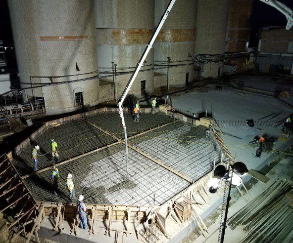 Crew placing concrete for a tank foundation inside an industrial building
