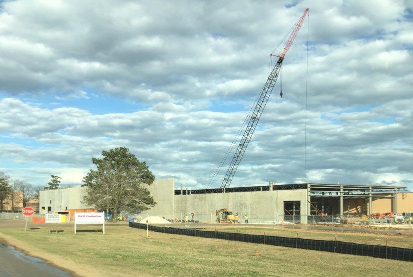 Crane setting a tilt-up concrete panel against a steel-framed building
